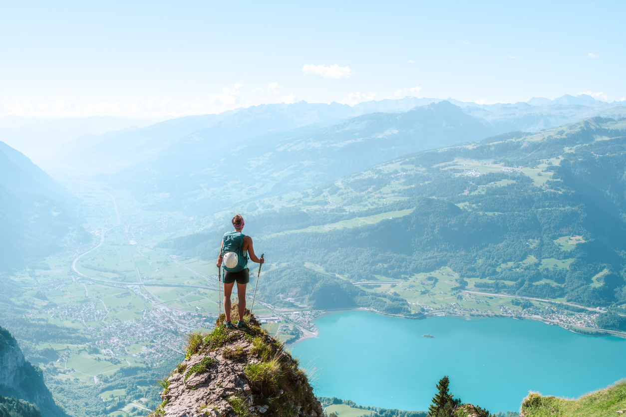 Woman stood on tip of rock looking out over lake